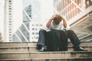 A stressed man sitting on stairs with his hands on his head
