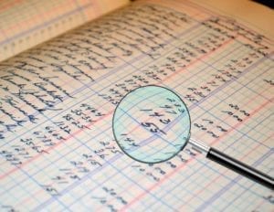 a magnifying glass inspecting a bookkeeping ledger for an audit