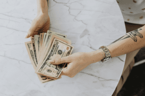person holding a stack of cash while sitting at a table. saving money on taxes