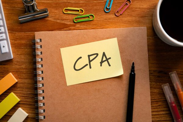 A notebook on a desk with a post-it note that says "CPA" on it.